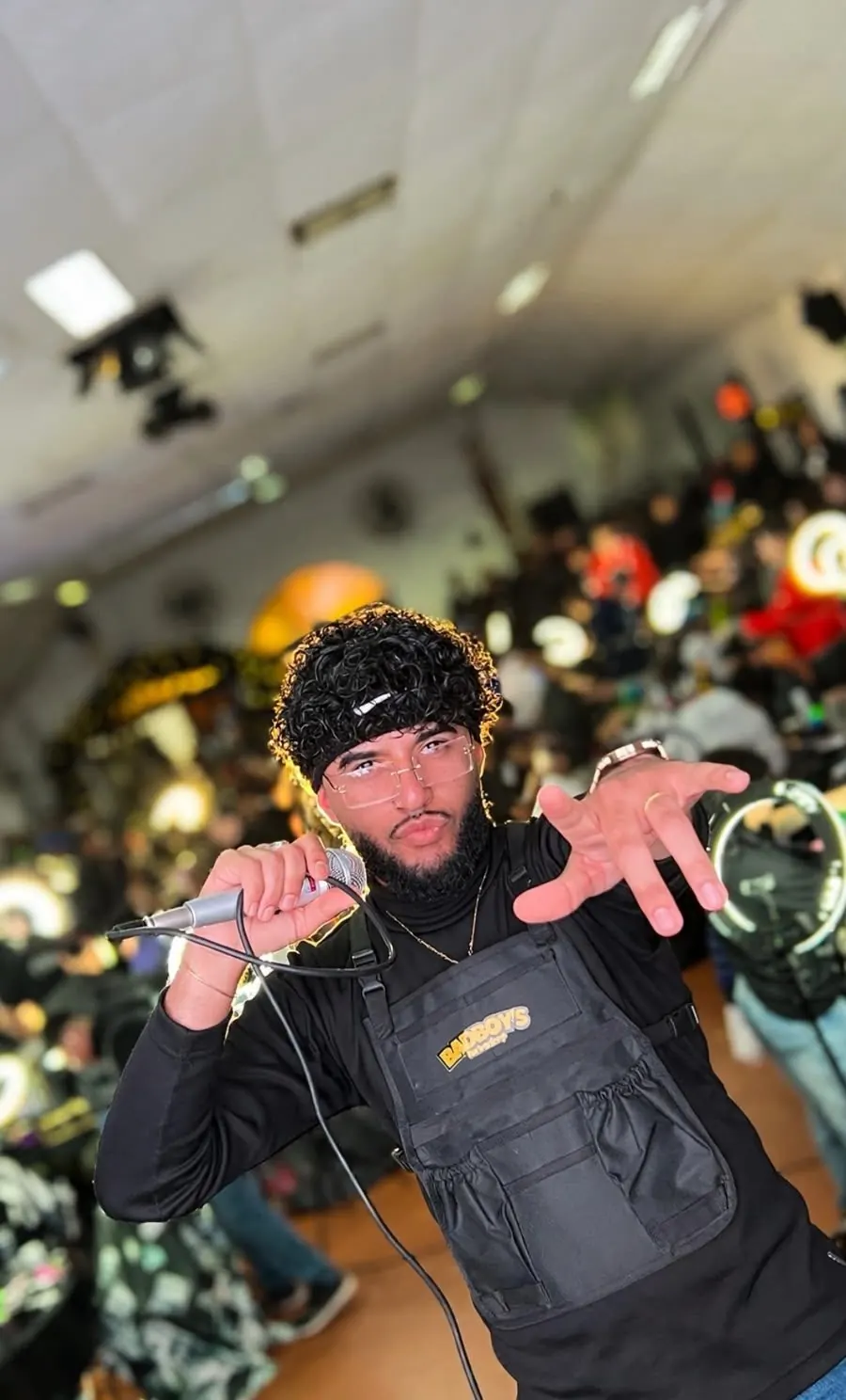 Ezequiel Farias con el micrófono en un evento de barbería, con el público atrás